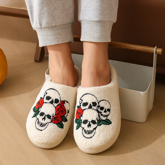 White slippers with skull and rose design worn by a person on a wooden floor.