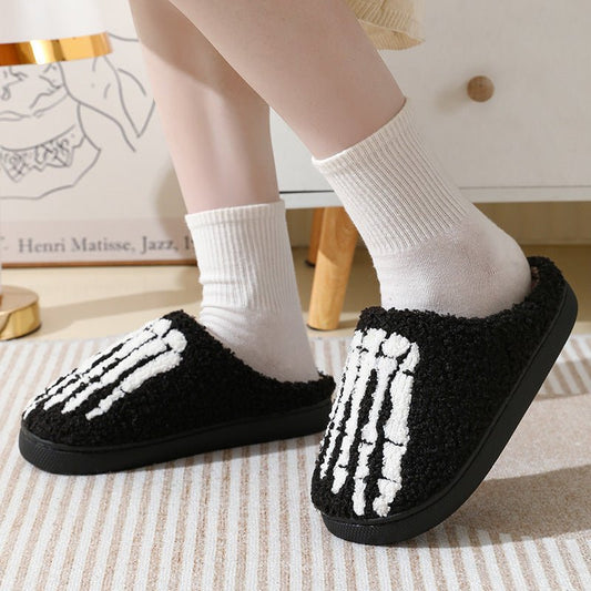 Black slippers with white skeleton design worn indoors on a striped rug.